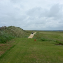 The view from the 1st tee. Note the proximity of the out-of-bounds fence (and beach immediately beyond) to the left, and the 18th green to the right. The ideal line from the tee (and shortest route home) is down the left-hand side, following the alignment of the cart path.