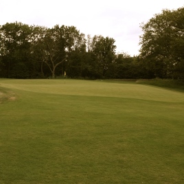 The view of the 15th green from front left showing the steep false front that feeds short approaches into the adjacent greenside bunker on the right.